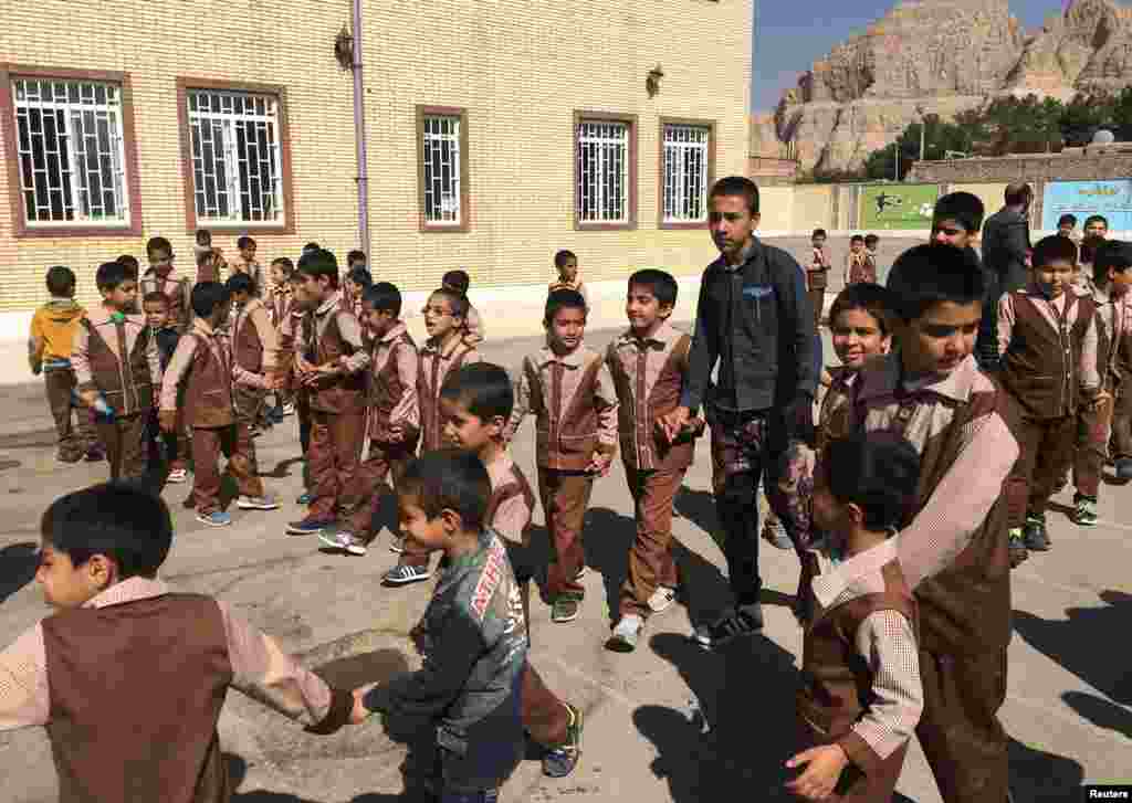 پسران ایرانی و افغان بیرون از مدرسه بعثت در کرمان بازی می&zwnj;&zwnj;کنند.