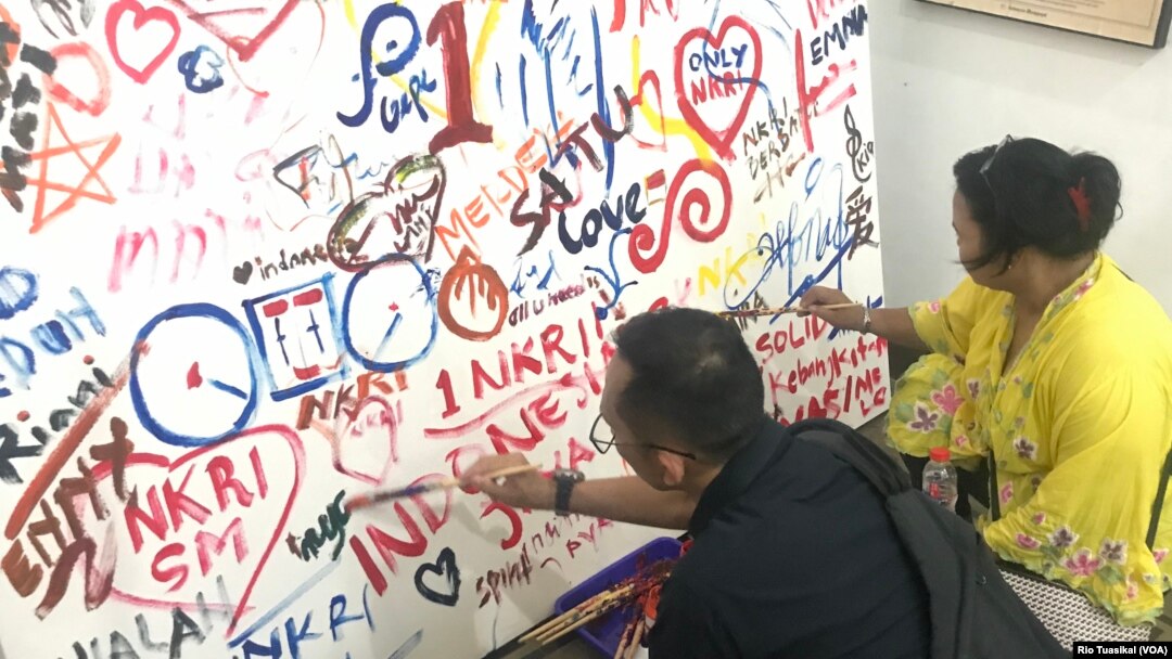Warga pengunjung ikut melukis mural dalam peringatan 111 tahun Hari Kebangkitan Nasional, Senin (20/5/2019), di Bandung. (VOA/Rio Tuasikal)