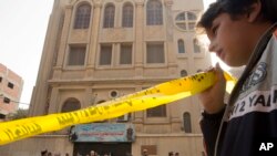 Seorang anak laki-laki memegang label kuning di sekitar lokasi di depan gereja Mar Mina, di Helwan, Kairo, Mesir, Jumat, 29 Desember 2017, di mana beberapa orang telah terbunuh dalam baku tembak di luar gereja. (AP Photo / Amr Nabil)