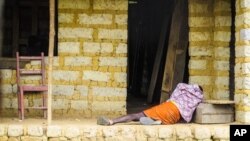 In this Tuesday, Oct. 21, 2014 file photo, a man suffering from the Ebola virus lies on the floor outside a house in Port Loko Community, on the outskirts of Freetown, in Sierra Leone. (AP Photo/Michael Duff, File)