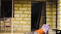 In this Tuesday, Oct. 21, 2014 file photo, a man suffering from the Ebola virus lies on the floor outside a house in Port Loko Community, on the outskirts of Freetown, in Sierra Leone.