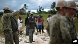 当地工人看着美国海军工程兵在利比里亚蒙罗维亚机场边修建一座25床位的医疗设施。（2014年9月27日）