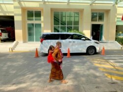 FILE - Two people walk past a vehicle of Prime Minister Hun Sen in Phnom Penh’s Calmette hospital in March 2021. (Aun Chhengpor/VOA Khmer)