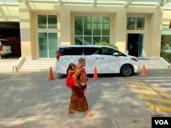 រូប​ឯកសារ៖ ស្ត្រីពីរ​នាក់​ដើរ​កាត់រថយន្តលោកនាយករដ្ឋមន្ត្រី ហ៊ុន សែន នៅមន្ទីរពេទ្យកាល់ម៉ែត រាជធានីភ្នំពេញ កាលពីខែមីនា ឆ្នាំ២០២១។ (អូន ឆេងប៉រ/វីអូអេ)