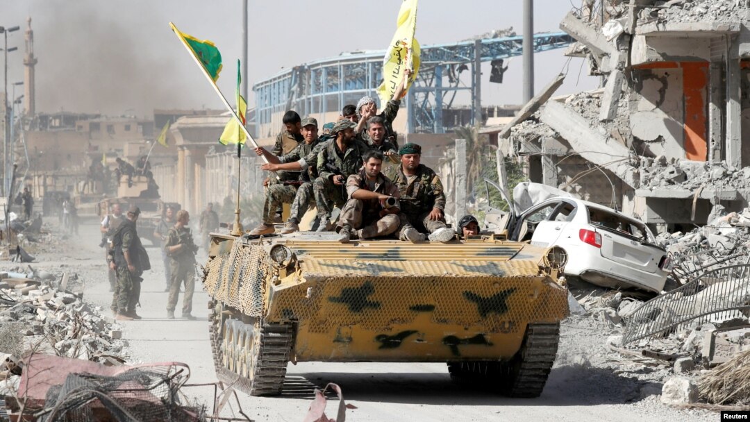 Pasukan Demokratik Suriah (SDF) yang didukung AS merayakan kemenangan di Raqqa, Suriah, hari Selasa (17/10).