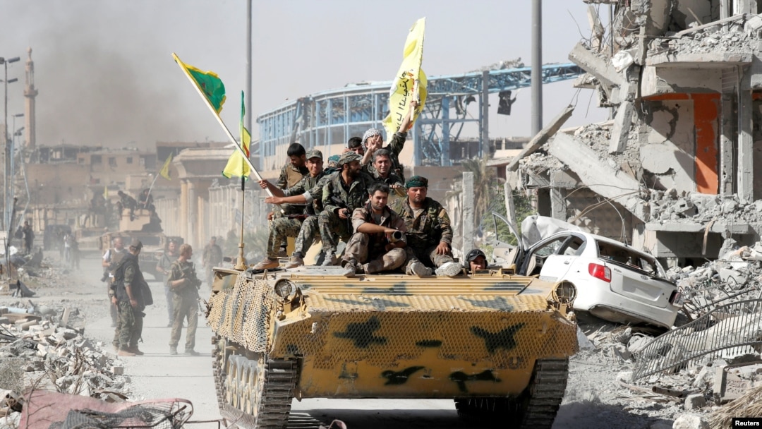 Pasukan Angkatan Darat Suriah (SDF) naik di atas kendaraan militer mereka saat merayakan kemenangan di Raqqa, Suriah, 17 Oktober 2017.