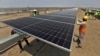 FILE - Workers install solar panels at the Khavda Renewable Energy Park of Adani Green Energy Ltd in Khavda, India, April 12, 2024.