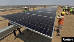 FILE - Workers install solar panels at the Khavda Renewable Energy Park of Adani Green Energy Ltd in Khavda, India, April 12, 2024.