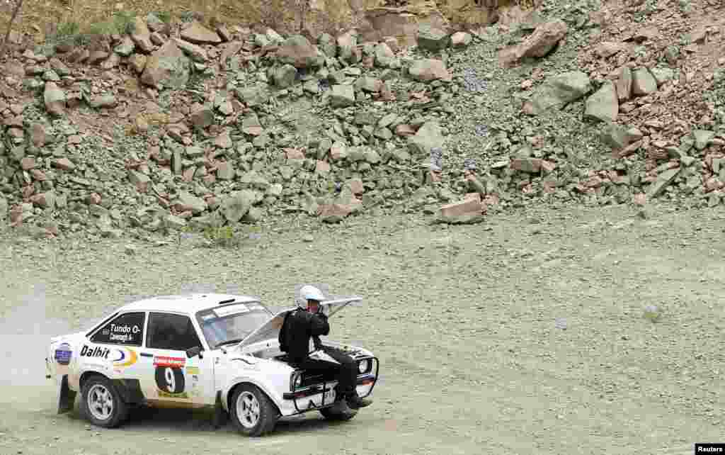 Kenyan rally driver Carl Tundo sits on the hood of the Ford Escort Mark 2 after a mechanical problem, on the fourth day of the Kenya Airways East African Safari Rally in Nairobi.