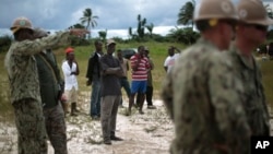 Local workers look on as a team or U.S. Navy engineers prepares the ground for a 25-beds medical facility they are building next to the airport in Monrovia, Liberia, Sept. 27, 2014. 