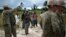 Local workers look on as a team or U.S. Navy engineers prepares the ground for a 25-beds medical facility they are building next to the airport in Monrovia, Liberia, Sept. 27, 2014. 