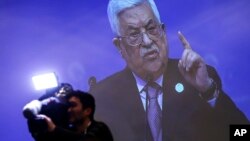 Un camarógrafo trabaja en el centro de prensa con el fondo de una transmisión en vivo del discurso del presidente palestino, Mahmoud Abás, en Estambul.