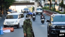 A policeman wearing a face mask stands guard at a checkpoint in Manila, Philippines, March 25, 2020, after the government imposed an enhanced quarantine as a preventive measure against the spread of the coronavirus.