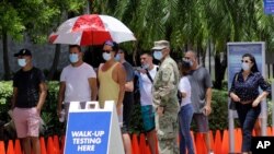 People wait in line at a walk-up testing site for COVID-19 during the new coronavirus pandemic, June 30, 2020, in Miami Beach, Fla. 