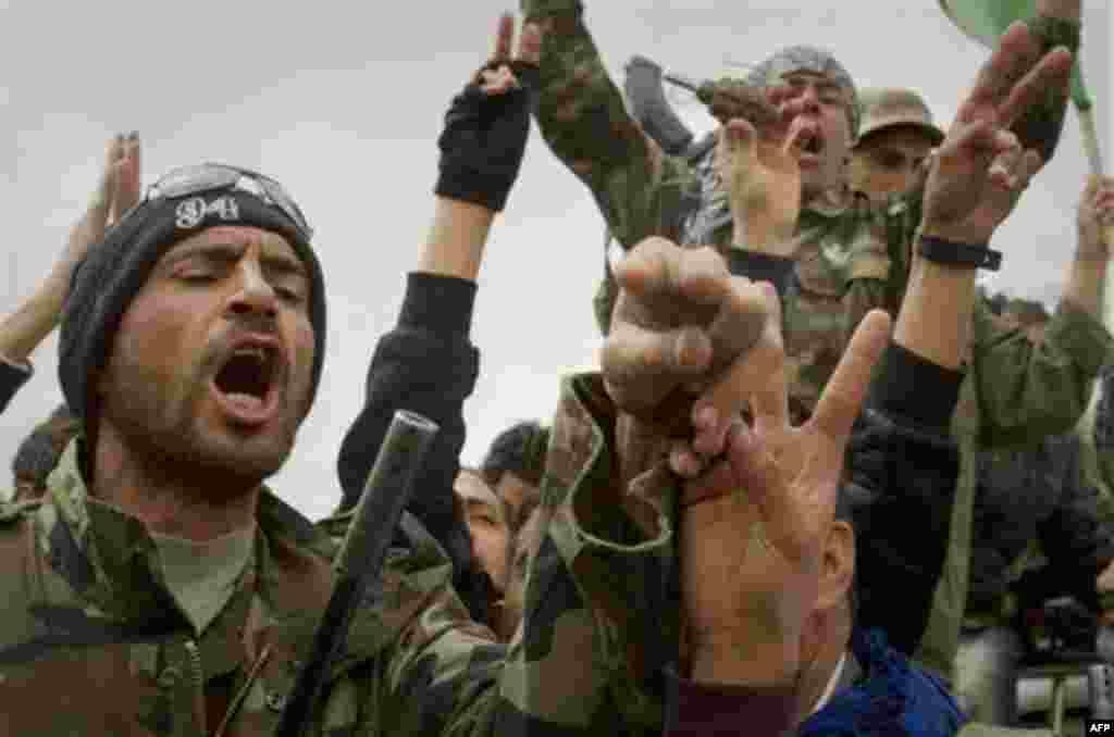 Libyan rebels react on the frontline of the outskirts of the city of Ajdabiya, south of Benghazi, eastern Libya, Monday, March 21, 2011. The international military intervention in Libya is likely to last "a while," a top French official said Monday, echoi