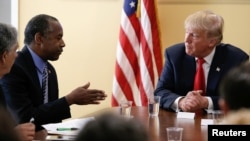 FILE - Republican presidential nominee Donald Trump listens to former presidential candidate Ben Carson during a meetig with local small-business leaders before a campaign rally in West Palm Beach, Fla., Oct. 13, 2016. 
