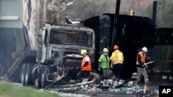 FILE - Workers clear debris from a highway in Lakewood, Colorado, April 26, 2019, following a deadly pileup involving a semi-truck hauling lumber. The driver, Rogel Aguilera-Mederos, was convicted in October of vehicular homicide stemming from the crash.