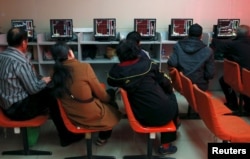 FILE - Investors look at computer screens showing stock information at a brokerage house in Shenyang, Liaoning province, April 13, 2015.