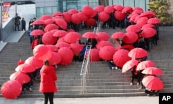 Middle school students make a formation with umbrellas in the shape of the red ribbon, the international symbol for AIDS awareness before a campaign to mark World AIDS Day in Seoul, South Korea, Tuesday, Dec. 1, 2015.