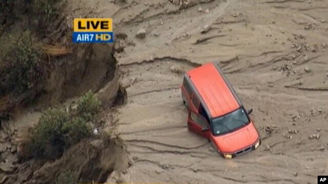 En esta imagen, tomada de un video de KABC-TV, se ve un vehículo varado en una calle cubierta de agua llena de lodo en Green Valley, California, 65 millas al noroeste del centro de Los Ángeles, el jueves, 15 de octubre de 2015.