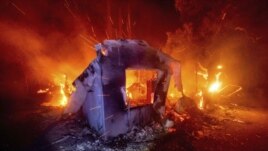 FILE - In this Aug. 19, 2020, file photo, flames from the LNU Lightning Complex fires consume a home in unincorporated Napa County, California.