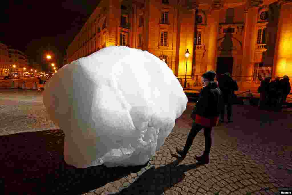 A woman looks at a mass of ice harvested from Greenland during an installation on Place du Pantheon for a project called Ice Watch Paris, in Paris, France.