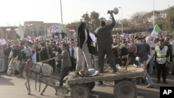 Protesters shout slogans from a donkey cart during a rally against the formation of a constituent assembly tasked with drafting a new constitution outside the Cairo convention center, March 24, 2012.