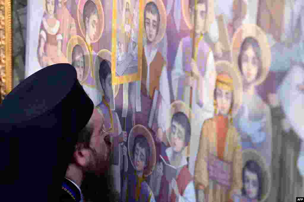 Seorang ulama mencium seorang ikon dalam upacara kanoninasi korban genosida Armenia di Echmiadzin di luar Yerevan.