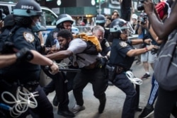Police detain protesters as they march down the street during a solidarity rally for George Floyd, May 30, 2020, in New York.