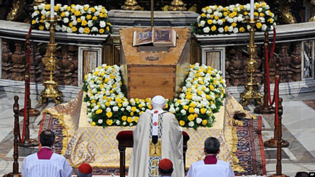 Pope Benedict XVI kneels in front of the coffin of the late Pope John Paul II inside St. Peter's Basilica at the Vatican, May 1, 2011