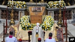 Pope Benedict XVI kneels in front of the coffin of the late Pope John Paul II inside St. Peter's Basilica at the Vatican, May 1, 2011