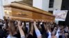 FILE - The body of Vittorio Casamonica is carried into a Roman Catholic basilica in a Rome suburb as a banner with his picture reads "You have conquered Rome, now conquer paradise" hangs to the entrance where the funeral was celebrated, Aug. 20, 2015.