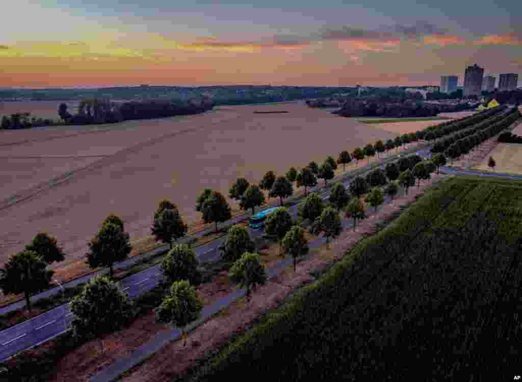 A bus drives along a road before sunrise on the outskirts of Frankfurt, Germany.