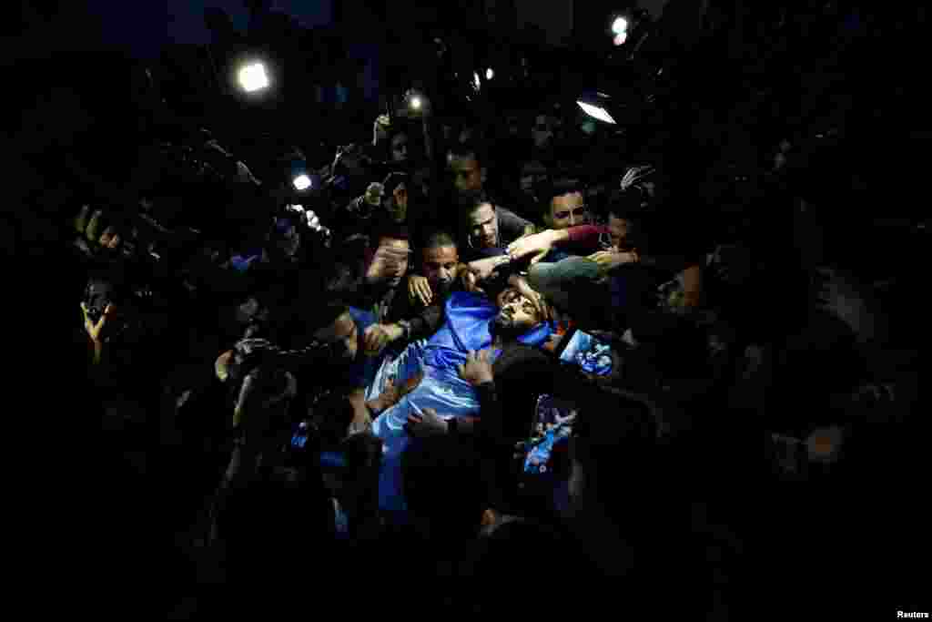 People carry the body of Palestinian journalist Ahmed Abu Hussein, 24, who died of wounds he sustained while covering a protest along the Gaza-Israel border, at a hospital in the northern Gaza Strip.