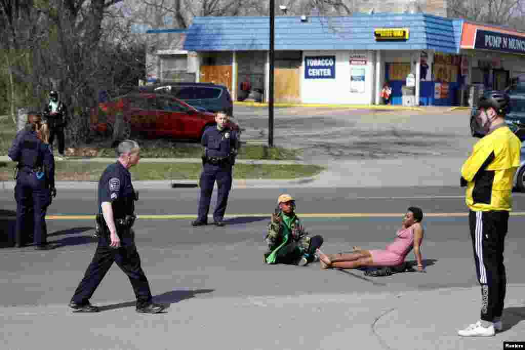 Phoenix Robles and Dorcas Monari block road traffic on Humboldt Avenue in front of the Brooklyn Center Police Department as protests continue days after former police officer Kim Potter fatally shot Daunte Wright, in Brooklyn Center, Minnesota, April 18, 2021.