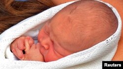 El bebé real, hijo de William y Kate, se entretiene con sus dedos el día en que fue presentado a la prensa. Este miércoles fue visitado por su visabuela, la reina Isabel II.