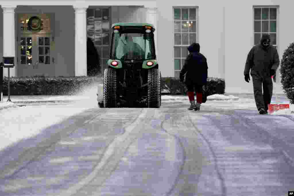 Des travailleurs du Service des parcs nationaux nétoient la neige sur la pelouse nord de la Maison-Blanche, le jeudi 4 janvier 2018, à Washington.