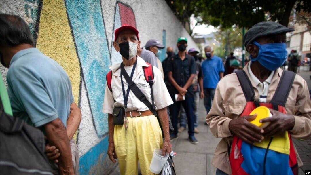 Con tapabocas, ancianos hacen fila para recibir una sopa en un comedor de beneficencia en la iglesia de San Miguel Arcángel en Caracas, el 28 de abril de 2021.
