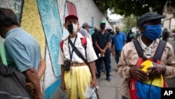 Con tapabocas, ancianos hacen fila para recibir una sopa en un comedor de beneficencia en la iglesia de San Miguel Arcángel en Caracas, el 28 de abril de 2021.