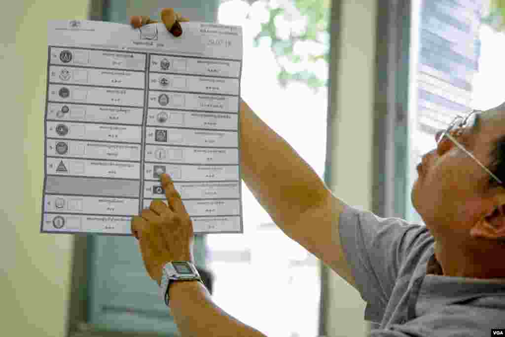 An election officer shows a voter selecting multiple parties resulting in a spoiled ballot, Boeng Keng Kong 2 commune, Chamkamon district, Phnom Penh, Cambodia, Sunday, July 29, 2018. (Khan Sokummono/VOA Khmer)