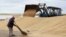 An employee sweeps wheat grain at the Aktyk farm outside Astana, Kazakhstan, September 10, 2013.