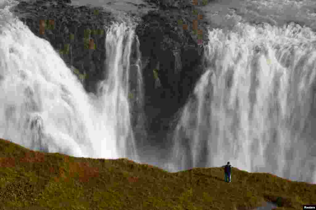A tourist takes a selfie in an area forbidden to walking, overlooking the waterfalls in Gullfoss, Iceland.