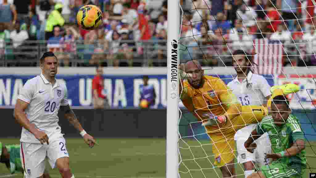 United States goalkeeper Tim Howard deflects a ball away from the goal .