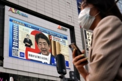 A public screen shows Japanese Prime Minister Shinzo Abe speaking at a press conference, May 25, 2020, in Tokyo.