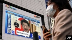 A public screen shows Japanese Prime Minister Shinzo Abe speaking at a press conference, May 25, 2020, in Tokyo. 