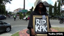 Seorang peserta aksi keprihatinan di Solo mengenakan pakaian dan kerudung hitam sambil membawa tulisan "RIP, KPK", 3 Maret 2015 (Foto: VOA/Yudha) 