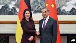 FILE - In this photo released by Xinhua News Agency, Chinese Foreign Minister Wang Yi, right, meets with German counterpart Annalena Baerbock before the seventh round of China-Germany Strategic Dialogue on Diplomacy and Security in Beijing Dec. 2, 2024.