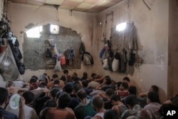 FILE - Suspected Islamic State members sit inside a small room in a prison south of Mosul, July 18, 2017.