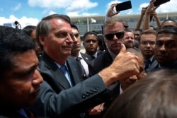 FILE - Brazil's President Jair Bolsonaro greets supporters after attending a Changing of the Guard at the Planalto Presidential Palace, in Brasilia, Nov. 28, 2019.