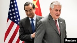 Secretary of State Rex Tillerson, right, and China's Foreign Minister Wang Yi walk to their seats before a meeting on the sidelines of a gathering of foreign ministers of the G-20 in Bonn, Germany, Feb. 17, 2017. 